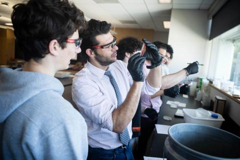 Lorenzo Servitje holds a pipette in a lab and examines it.